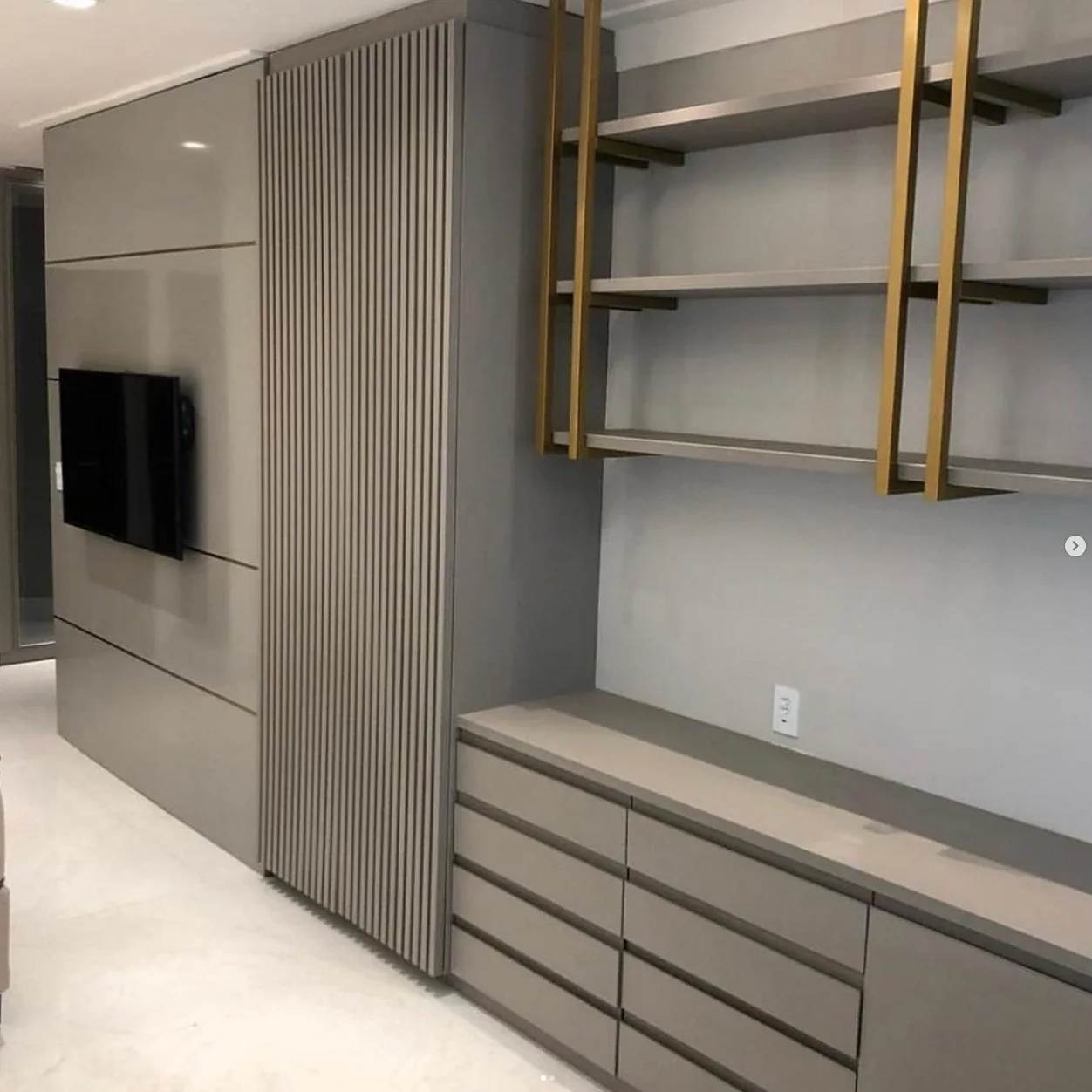 Painel fendi com TV embutida, coluna ripada e prateleiras douradas